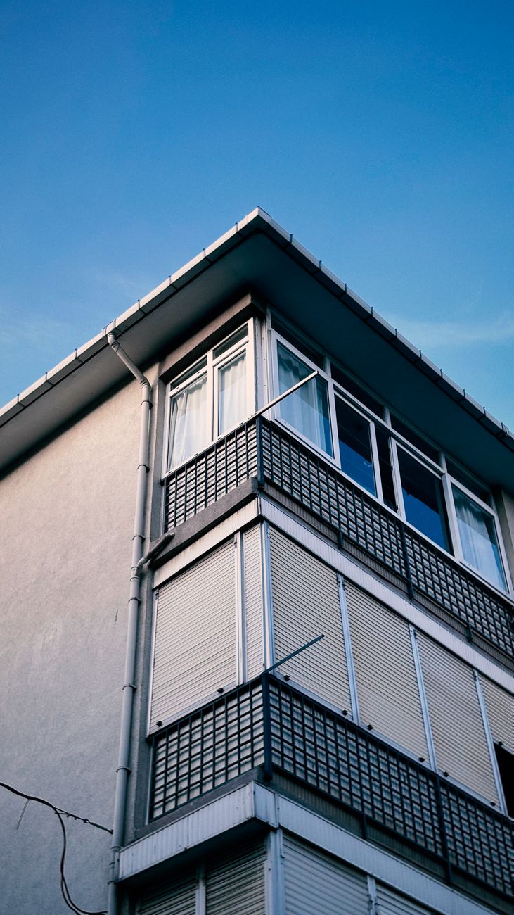 Modern corner building with grid design and clear blue sky.